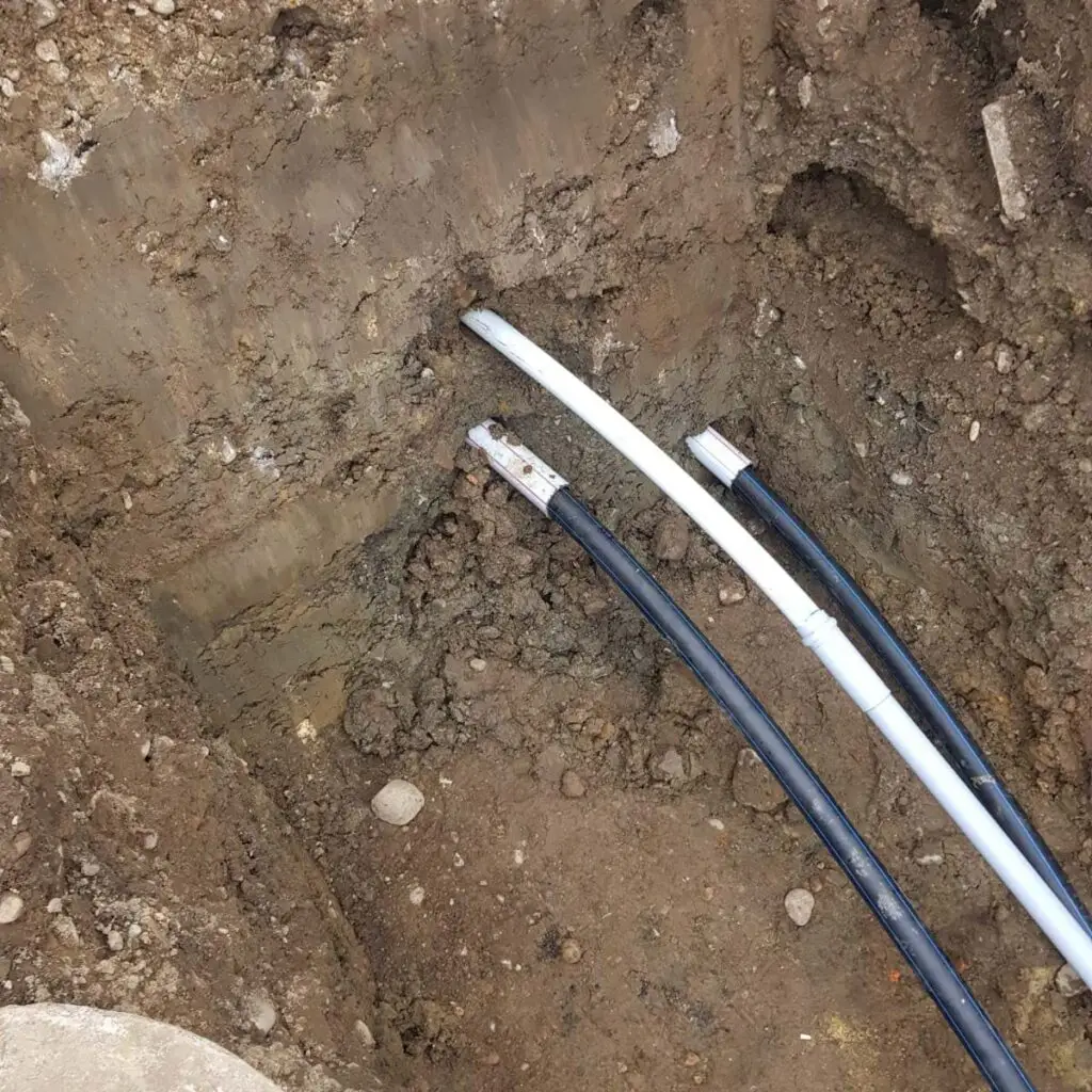 Im Graben befinden sich drei Rohre, diese wurden bereits verlegt und ragen noch aus dem Boden heraus, bis die nächsten Arbeitsschritte durchgeführt wird.